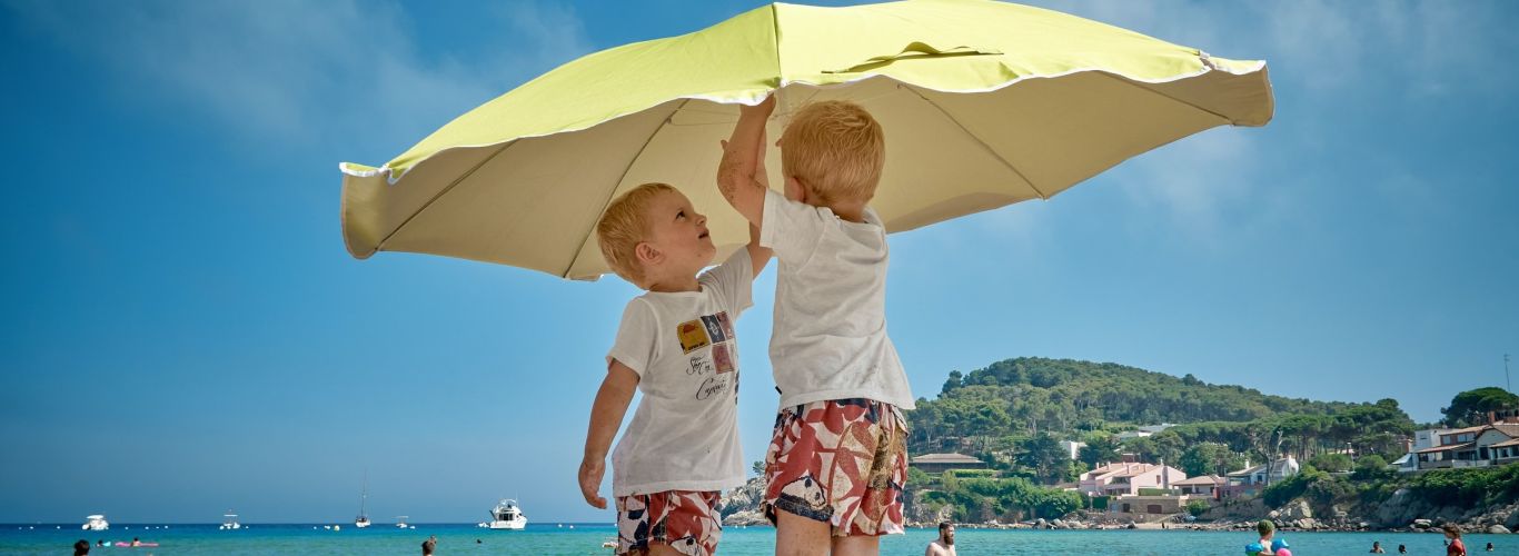 Kids on beach putting up umbrella