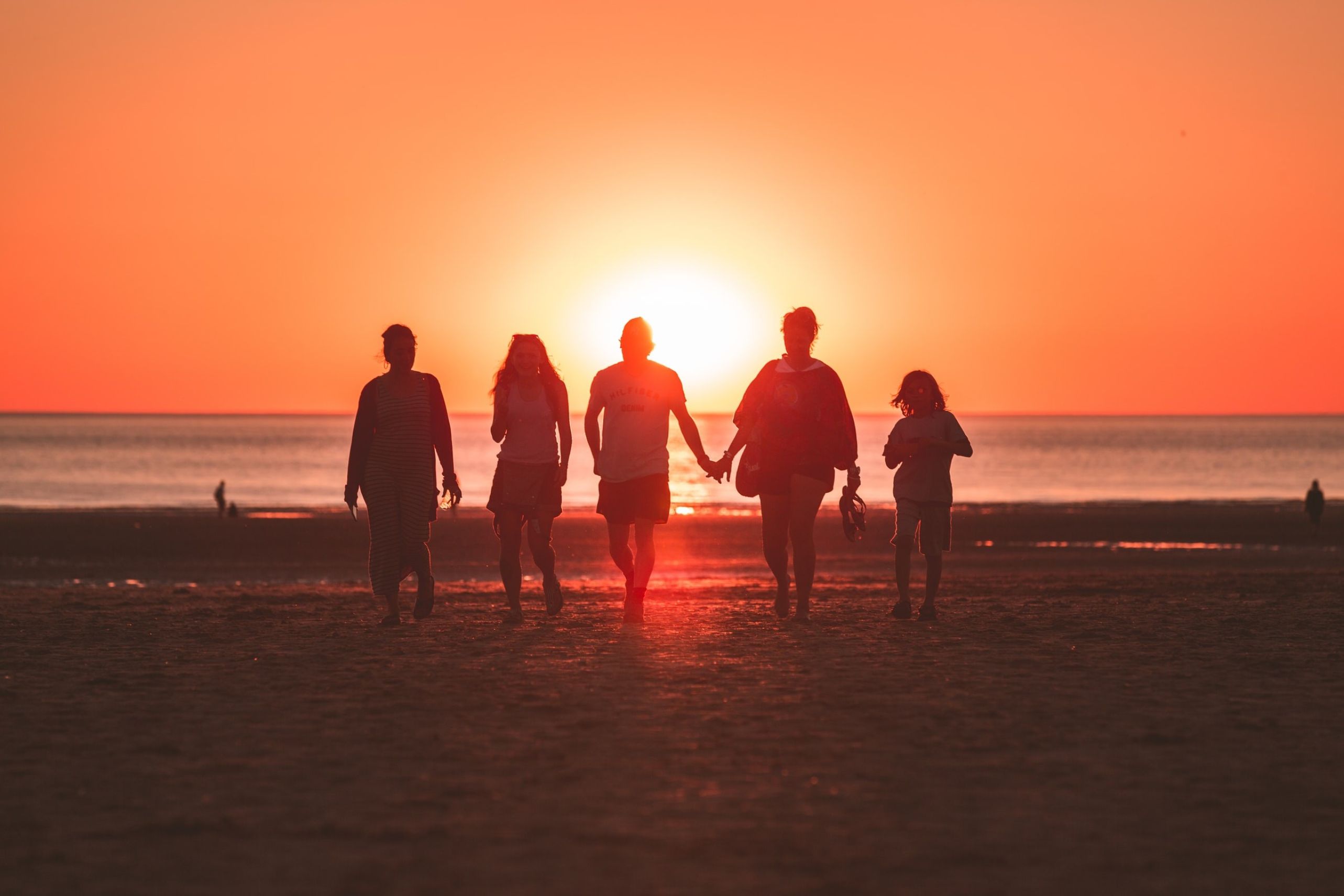 Family walking on beach in sunset