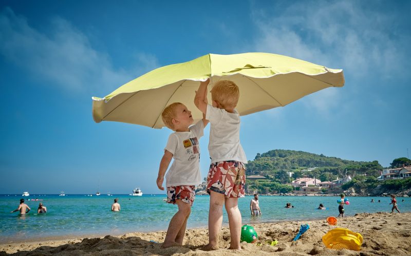 Kids on beach putting up umbrella